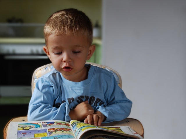 Маленький мальчик читает интересную книгу