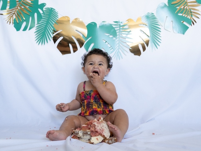 Маленькая девочка ест торт на белом фоне