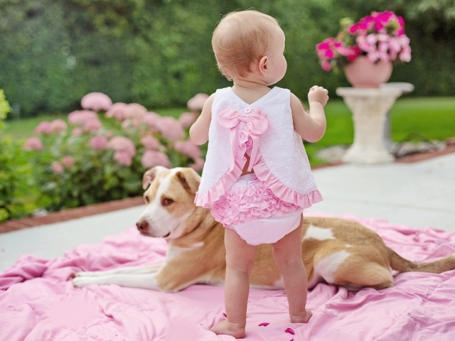 Маленькая девочка с собакой на розовом покрывале
