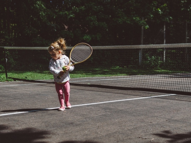 Маленькая девочка с ракеткой на поле