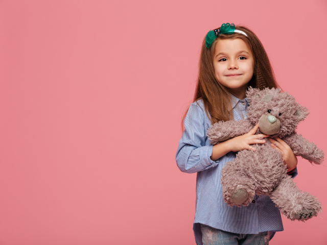 Маленькая девочка с игрушкой на розовом фоне