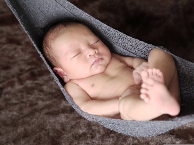 Новорожденный спящий малыш в вязаном гамаке