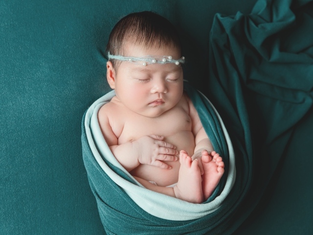 Фотография спящей новорожденной девочки на зеленом фоне