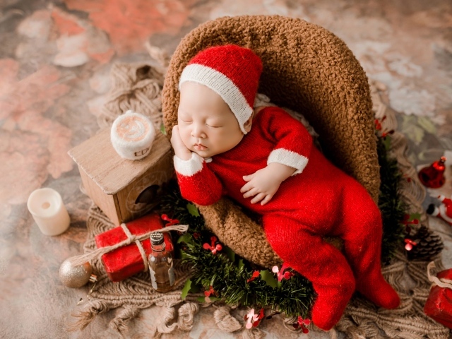 Спящий новорожденный ребенок в красном новогоднем костюме