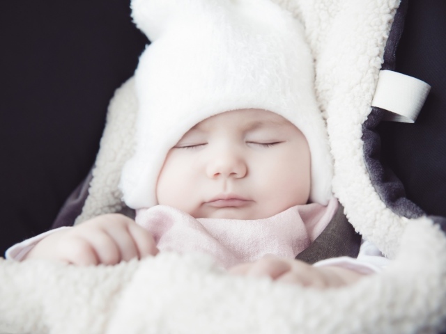 Спящий новорожденный ребенок в белой шапке