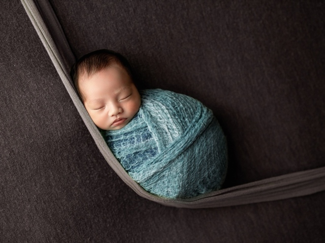 Маленький спящий ребенок завернут в покрывало