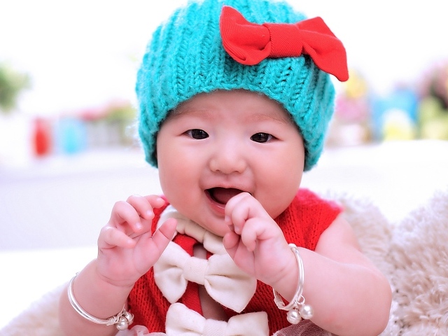 Улыбающаяся девочка в зеленой вязаной шапке