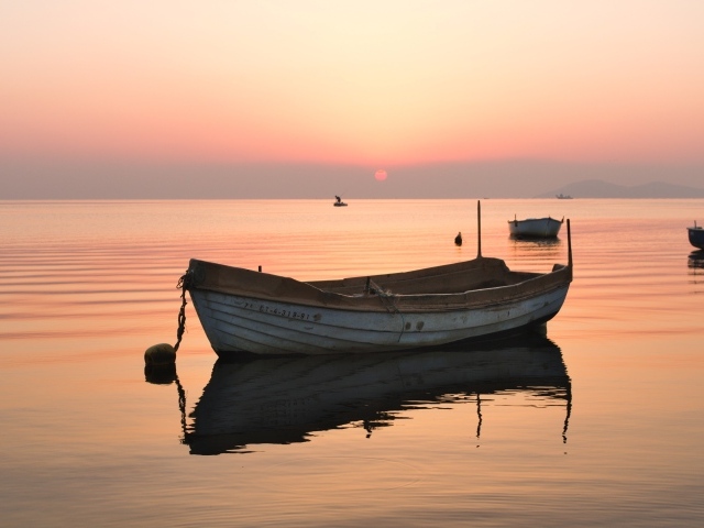 Старая лодка стоит на воде на закате солнца