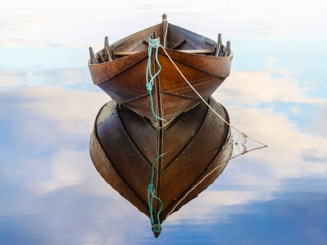 Большая деревянная лодка отражается в воде