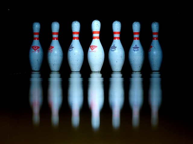 Кегли для боулинга отражаются в черной поверхности 