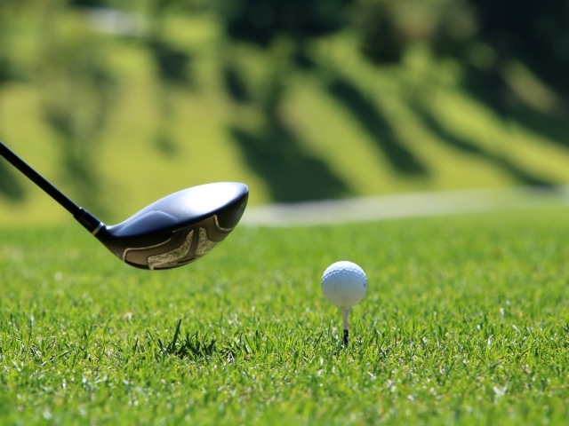 Мяч и клюшка для гольфа на зеленой траве
