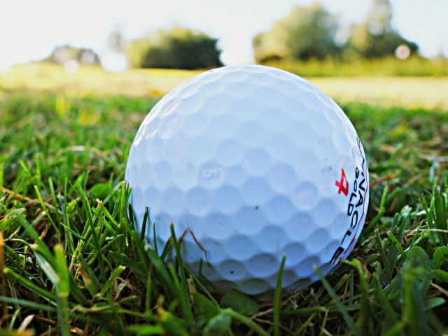 Белый мяч для гольфа в зеленой траве