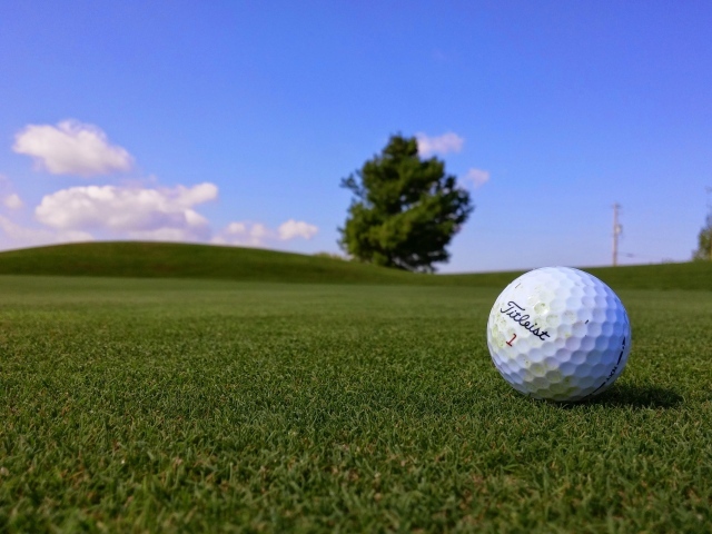 Белый мяч для гольфа на зеленой траве