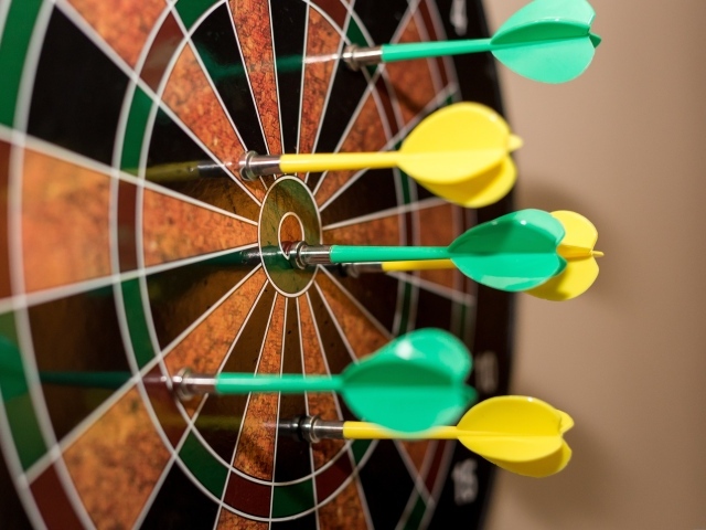 Желтые и зеленые дротики в мишени 