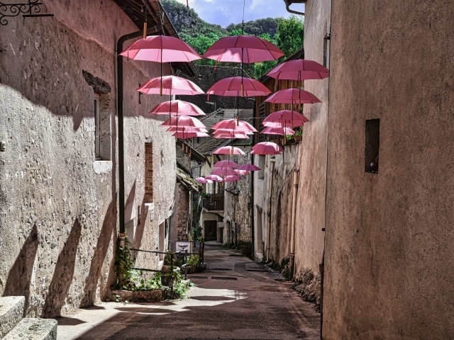 Розовые зонтики украшают узкую улицу