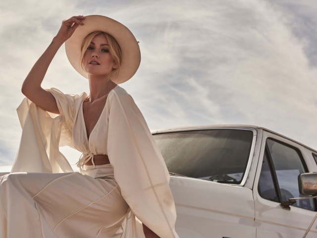 Актриса Кэтрин Макнамара в белом костюме сидит на автомобиле