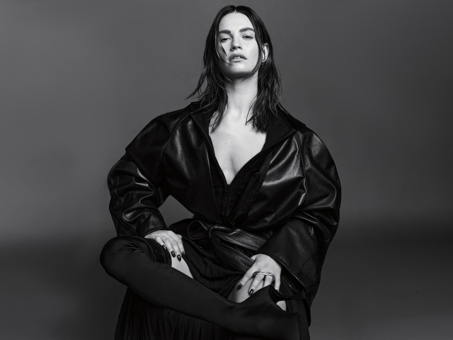 Актриса Лили Джеймс в черном наряде на сером фоне