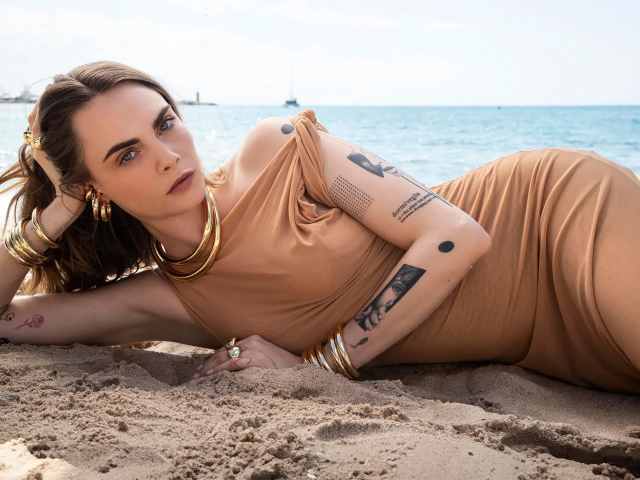Британская актриса Кара Делевинь лежит на песке на пляже