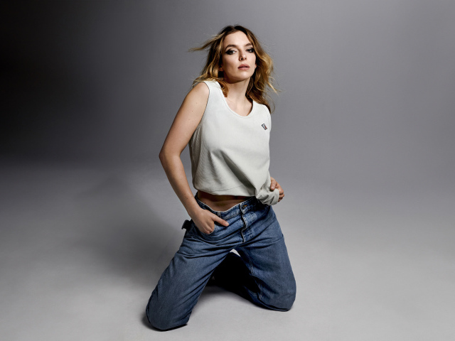 Британская актриса Джоди Комер в джинсах на сером фоне