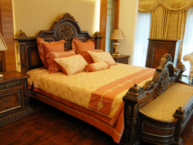 Большая деревянная кровать в спальне с оранжевым интерьером