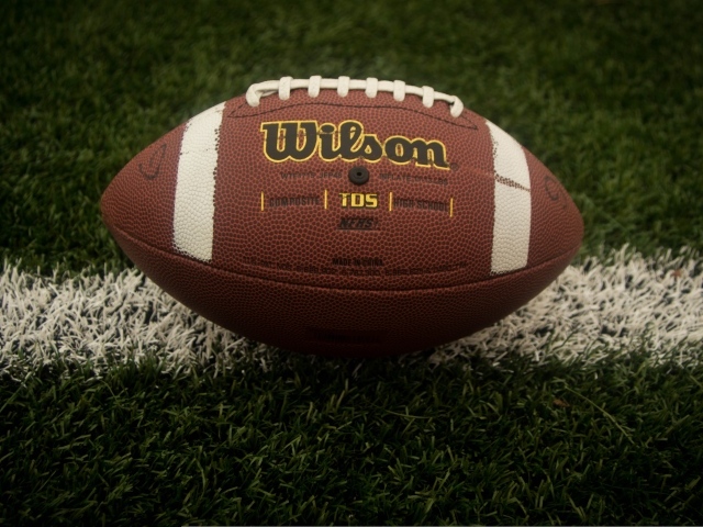Кожаный мяч для американского футбола на зеленой траве