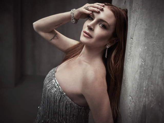 Рыжеволосая актриса Линдси Лохан стоит у стены