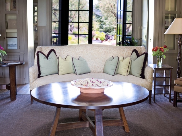 Круглый деревянный стол в гостиной с диваном