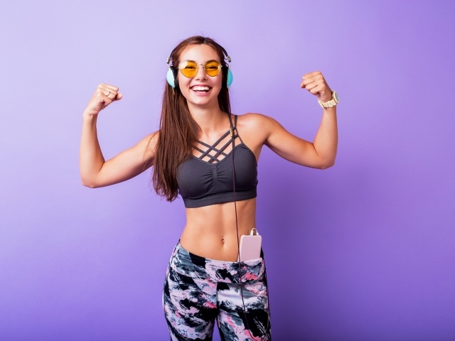 Улыбающаяся спортивная девушка слушает музыку