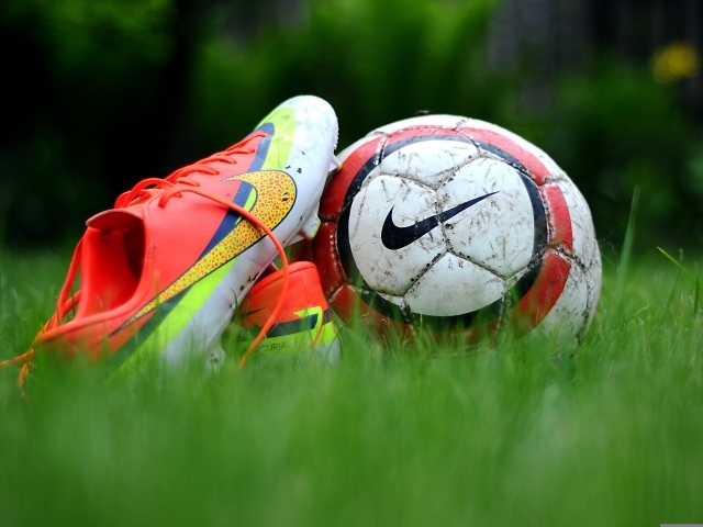 Футбольный мяч и бутсу на зеленой траве