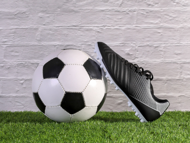 Футбольный мяч и спортивная обувь у стены