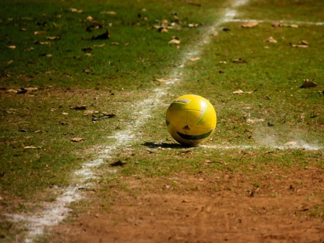 Желтый мяч на футбольном поле осенью 