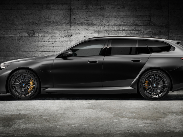 Вид сбоку на черный автомобиль BMW M5 Touring 2024 года