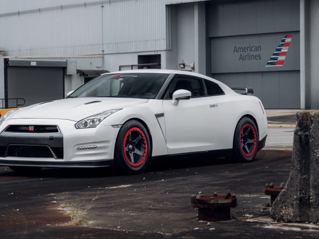 Белый автомобиль Nissan GT-R у гаража