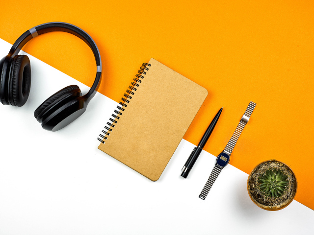 Наушники, блокнот, ручка, часы и цветок на фоне