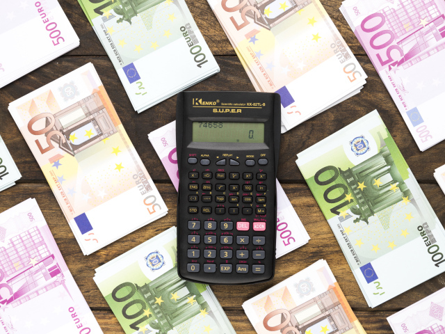 Калькулятор и купюры евро на деревянном столе