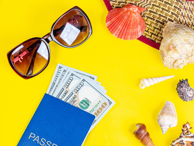 Очки, доллары с паспортом и ракушки на желтом фоне