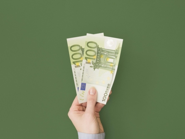 Две купюры по сто евро на зеленом фоне