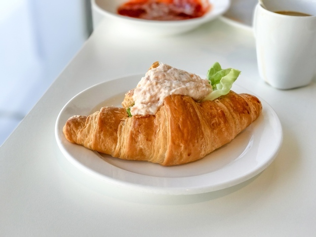 Круассан с начинкой на белой тарелке на завтрак 