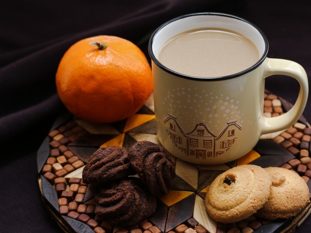 Чашка какао на тарелке с мандарином и печеньем