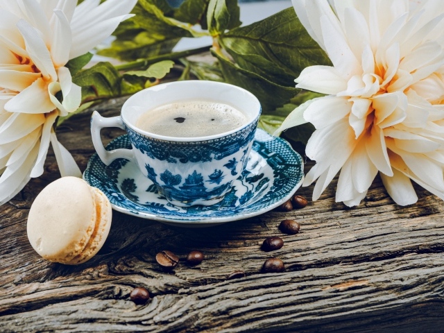 Чашка кофе с макарунами на столе с цветами