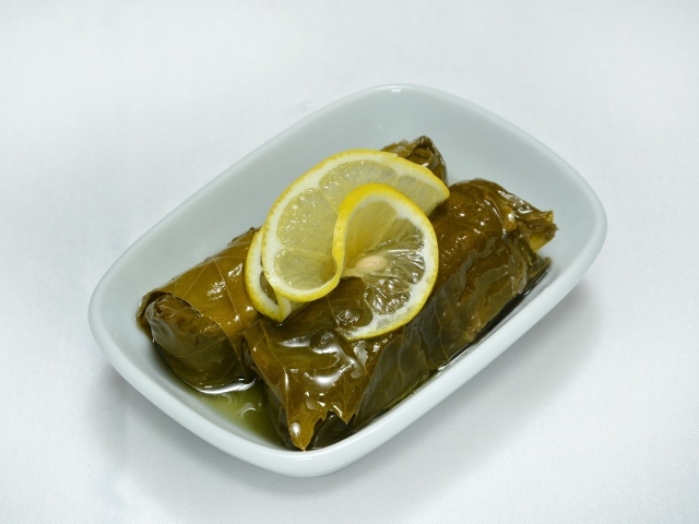 Долма с лимоном с тарелке на сером фоне