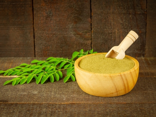 Порошок моринга на столе с листьями