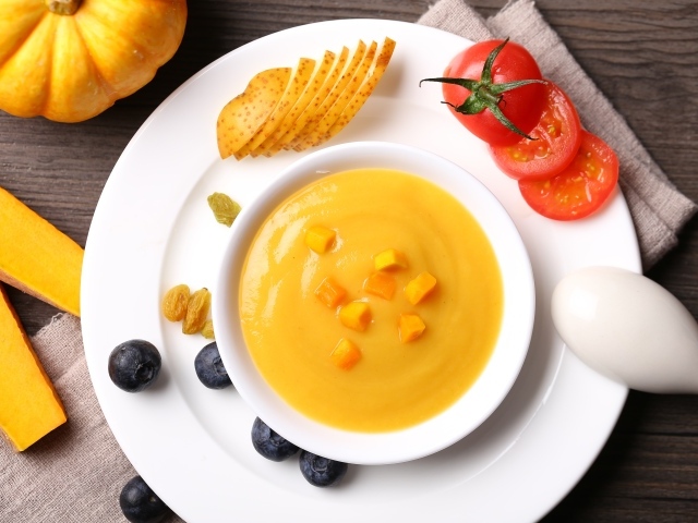 Тыквенный суп пюре на тарелке с картофелем и помидором