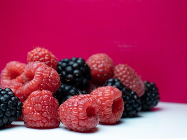 Ягоды черники и малины на красном фоне