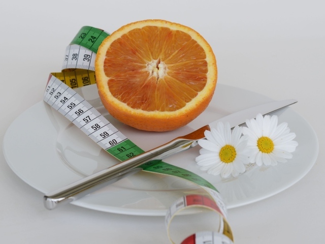 Половина апельсина на тарелке с сантиметром