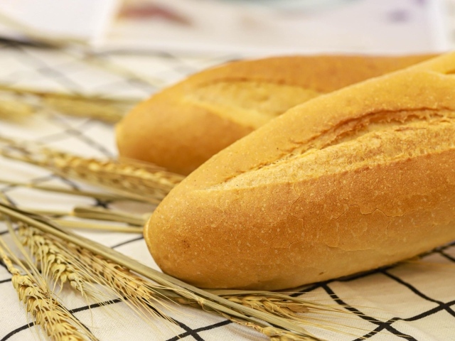 Два батона на столе с колосьями пшеницы
