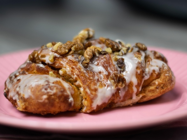 Круассан с кремом и грецкими орехами на розовой тарелке