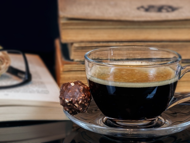 Чашка кофе на тарелке с шоколадной конфетой