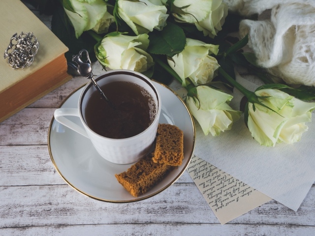 Чашка кофе на столе с букетом белых роз