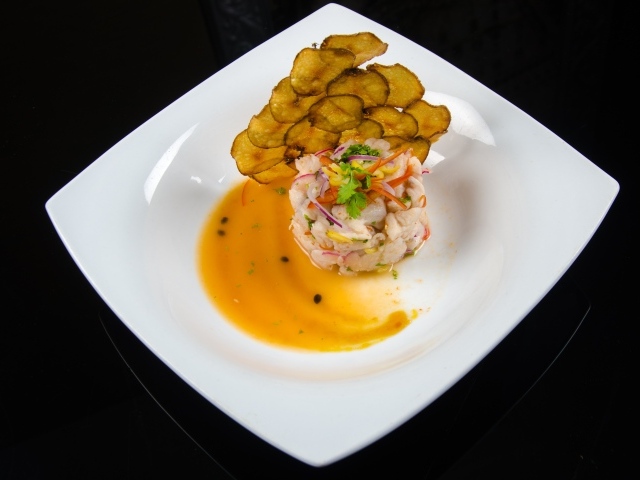 Морепродукты с соусом на большой белой тарелке на черном фоне